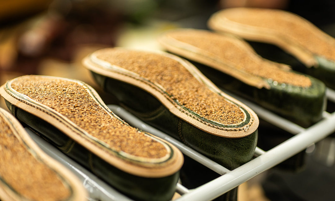 row of green leather boots upside down on production racks with cork filling
