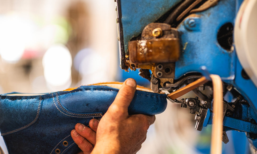 hand guiding a blue textured leather boot along welting machine