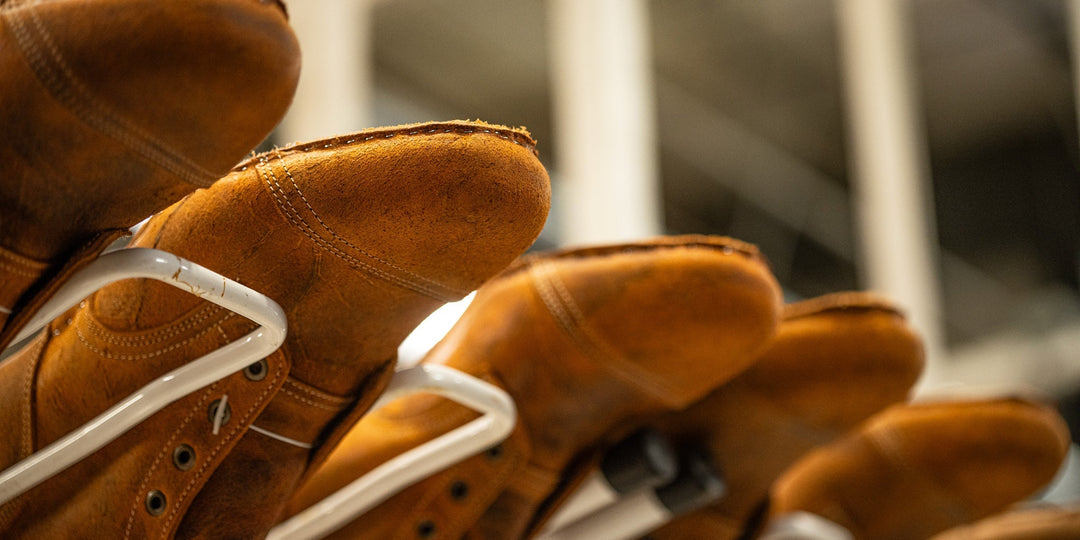 view from below of production rack filled with textured orange coach rambler leather boots in process