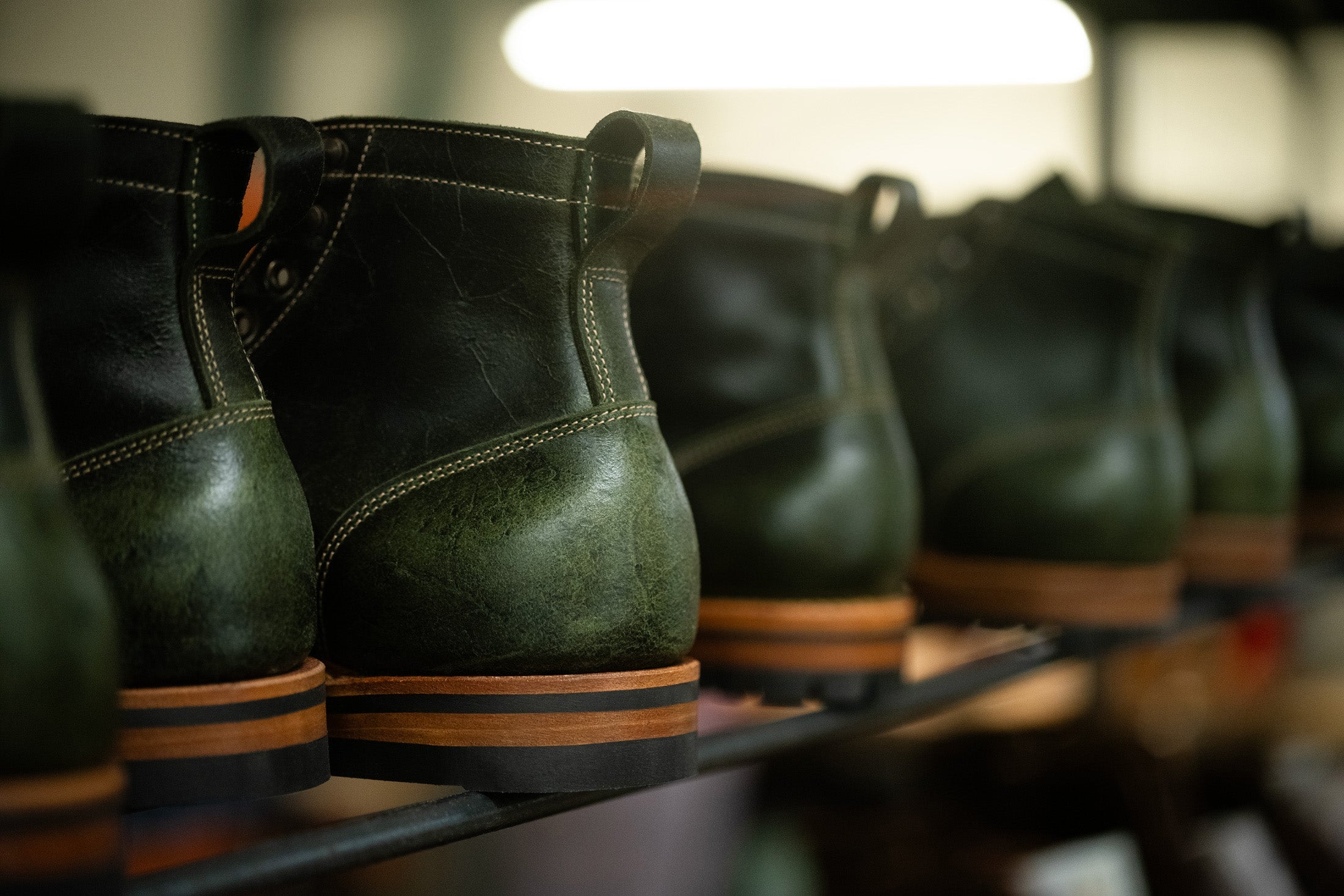 metal rack with row of green textured leather boots