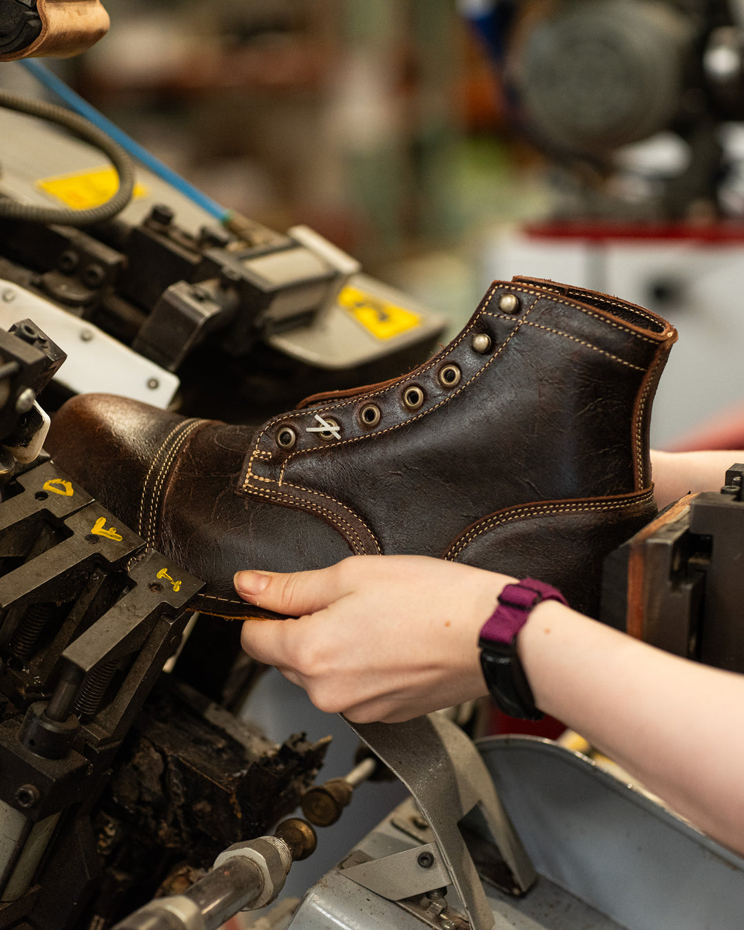 hands guiding textured brown leather upper in toe lasting machine