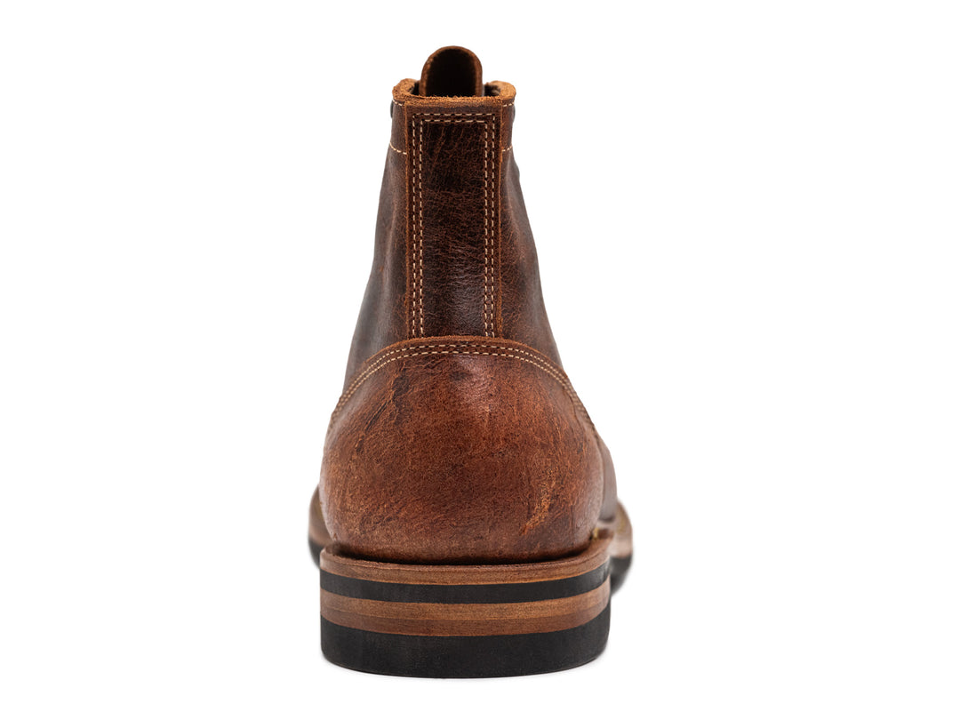 rear view of brown textured leather boot on white background