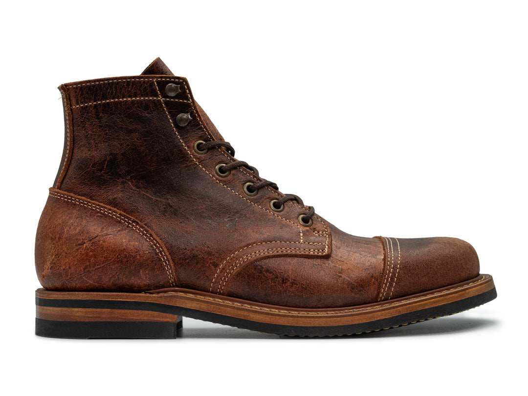 textured brown leather boot on white background