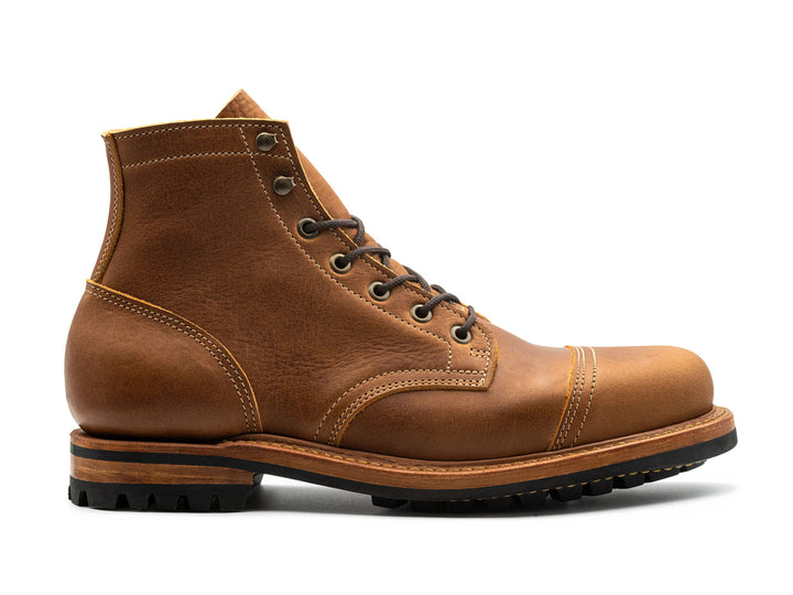 side view of tan brown leather cap toe boot on white background