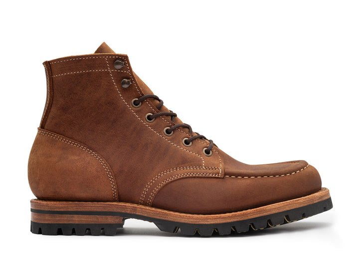 side view of brown leather moc toe boot on white background