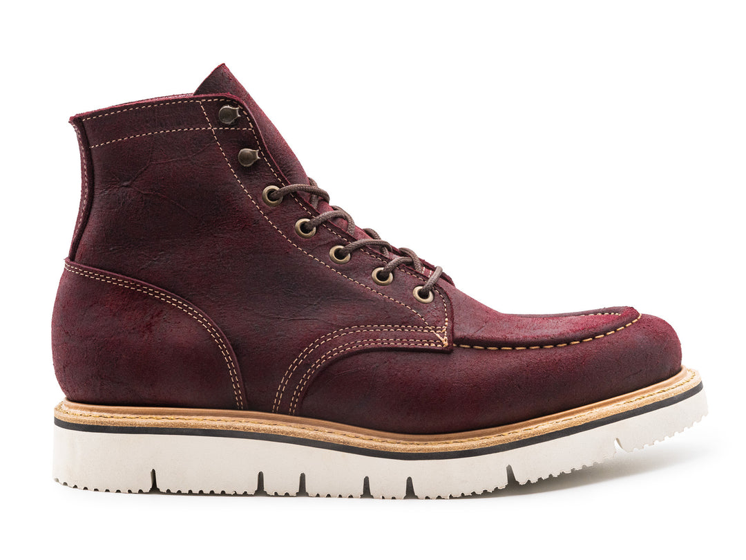 side view of burgundy rambler leather moc toe boot on white background