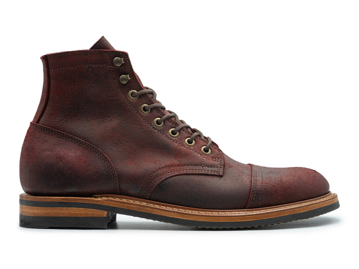 side view of dark scarlet red leather cap toe boot on white background