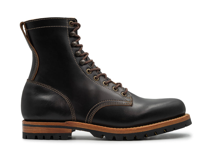 side view of tall black leather boot on white background