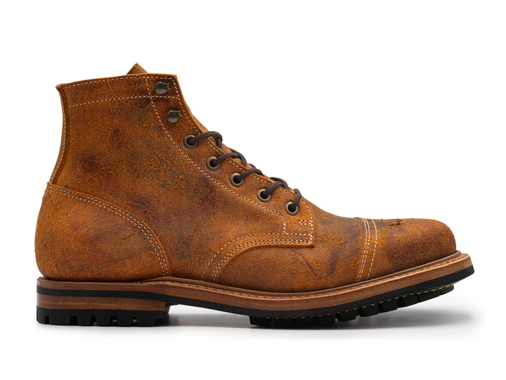 side view of single textured orange leather boot with black outsole on white background