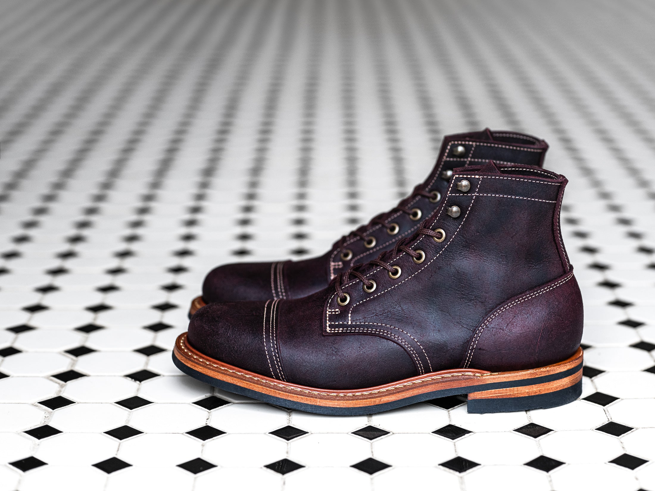 pair of garnet rambler boots on black and white tile