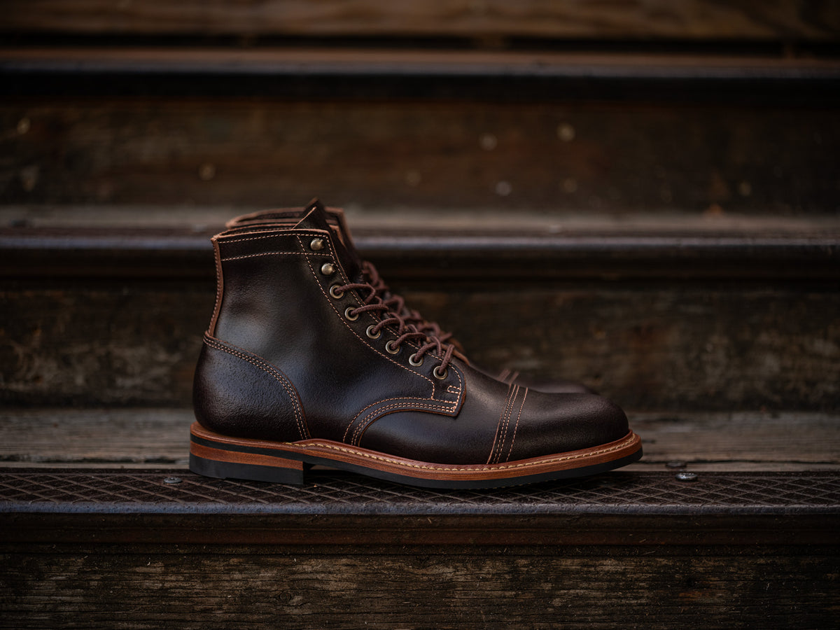 pair of brown waxed flesh boots sitting on wood and metal steps
