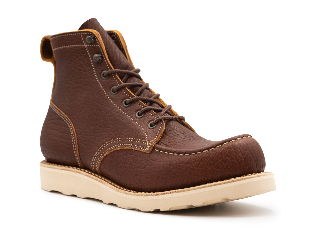 three quarter view of brown textured leather moc toe boot on white background