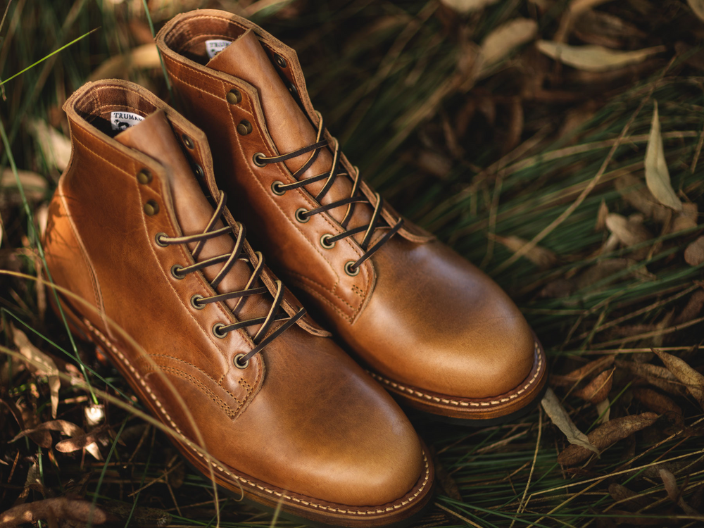 pair of tan boots sitting on fall grass
