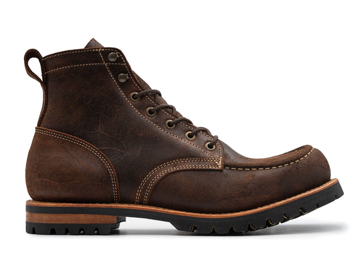 side view of textured brown leather moc toe boots on white background