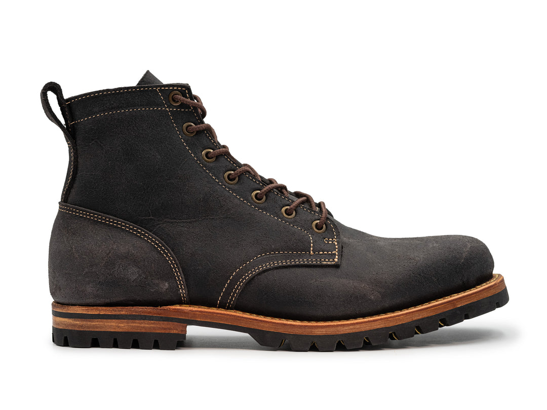 side view of textured gray leather boot on white background