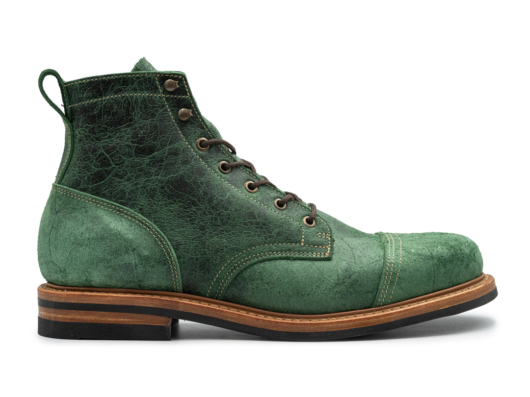 side view of textured green leather boot on white background