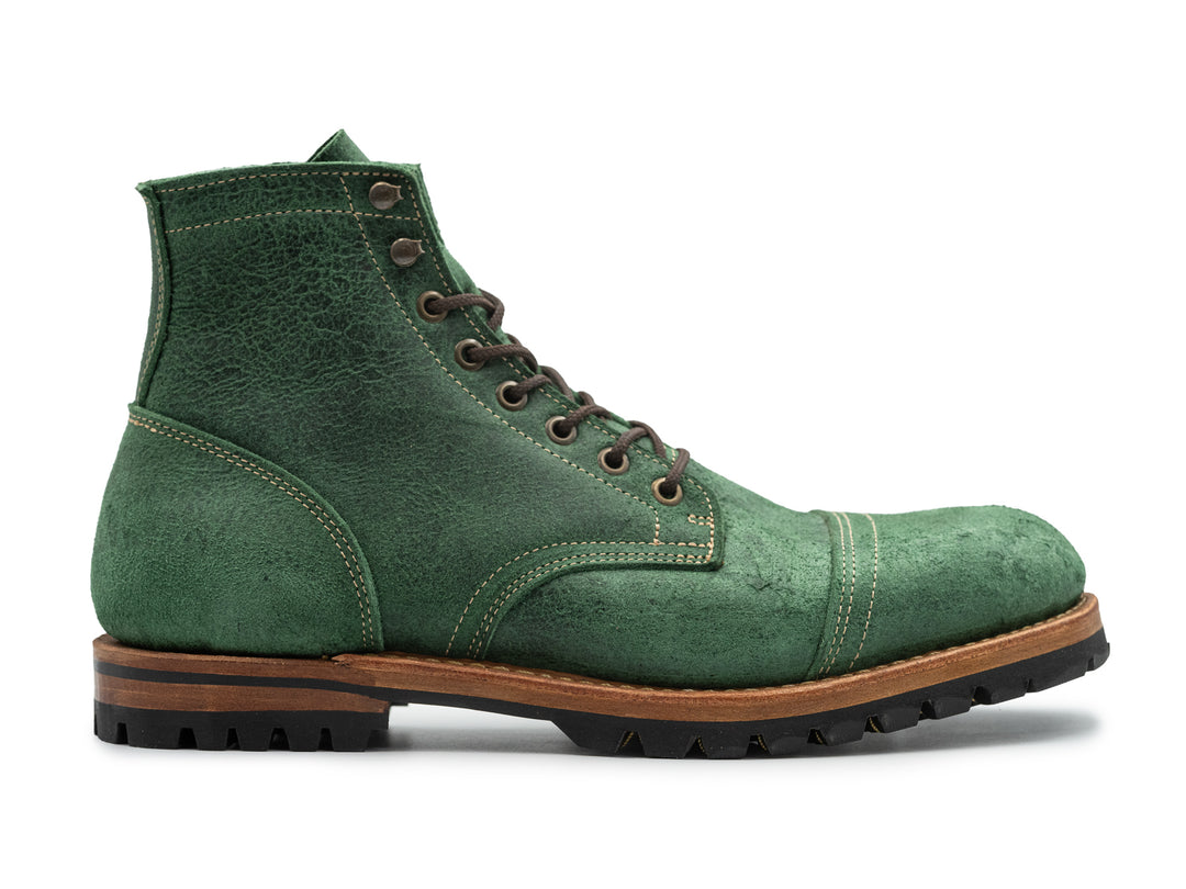 side view of textured green leather boot on white background
