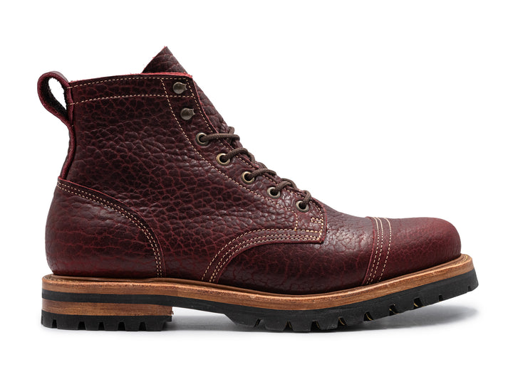 side view of textured burgundy bison leather boot on white background