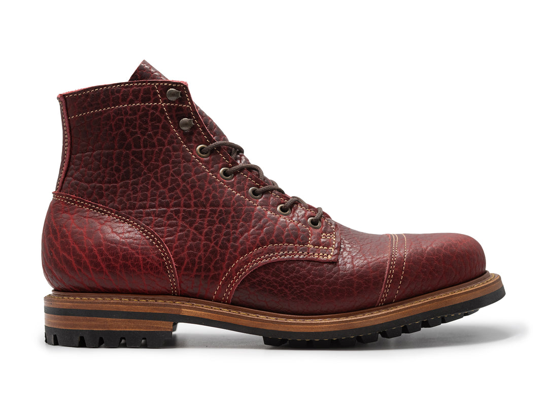side view of textured burgundy bison leather boot on white background