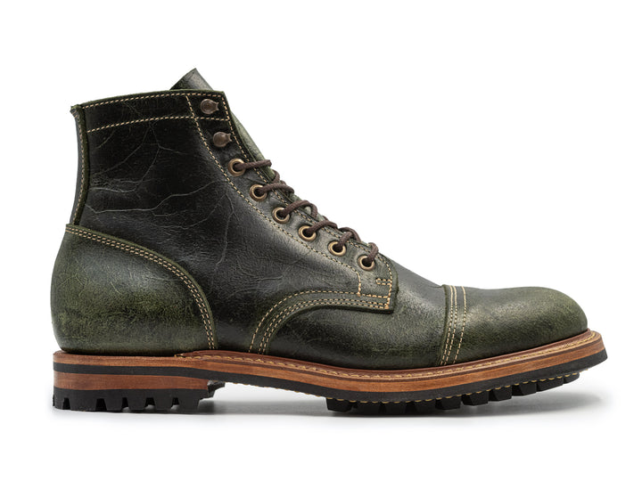 side view of textured green leather boot on white background